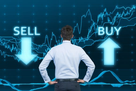 A man looking at a graph with the words buy and sell to the sides.