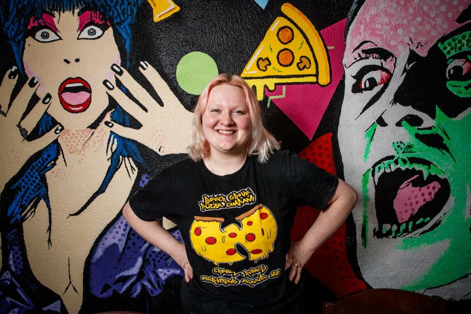 Daisy Gomez, a chef at Beech Grove Pizza Company, poses Friday, Dec. 3, 2021, in front of various painted characters inside the Main Street restaurant. 