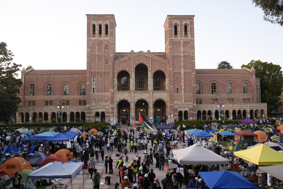 Demonstrators walk in an encampment on the UCLA campus after clashes between pro-Israel and pro-Palestinian groups, Wednesday, May 1, 2024, in Los Angeles. (AP Photo/Jae C. Hong)