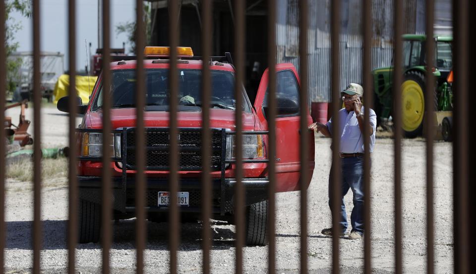 In this Sept. 6, 2012, photo, cotton farmer Teofilo “Junior” Flores stands on one side of the U.S.-Mexico border fence that passes across his property in Brownsville, Texas. Since 2008, hundreds of landowners on the border have sought fair prices for property that was condemned to make way for the fence, but many of them received initial offers that were far below market value. (AP Photo/Eric Gay)