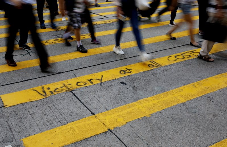 Pedestrians walk over graffiti on a crossing in Hong Kong