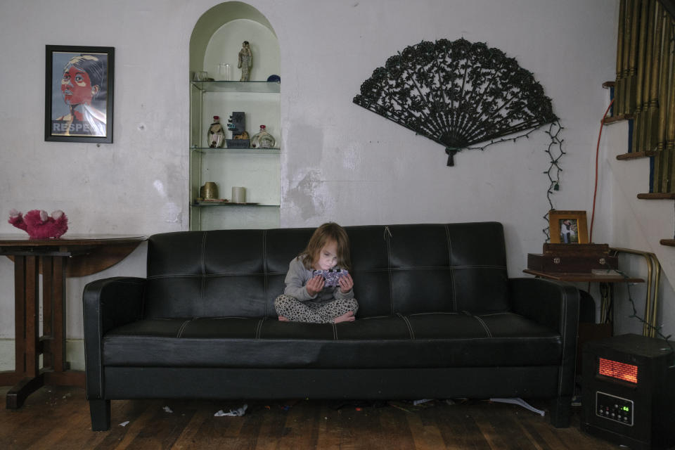 Honesty&nbsp;watches an episode of "SpongeBob SquarePants" on Fritz's phone. In August, Fritz finally received the deed to the house she was squatting in with her family due to a Detroit Land Bank Authority program called BuyBack. (Photo: Sean Proctor for HuffPost)