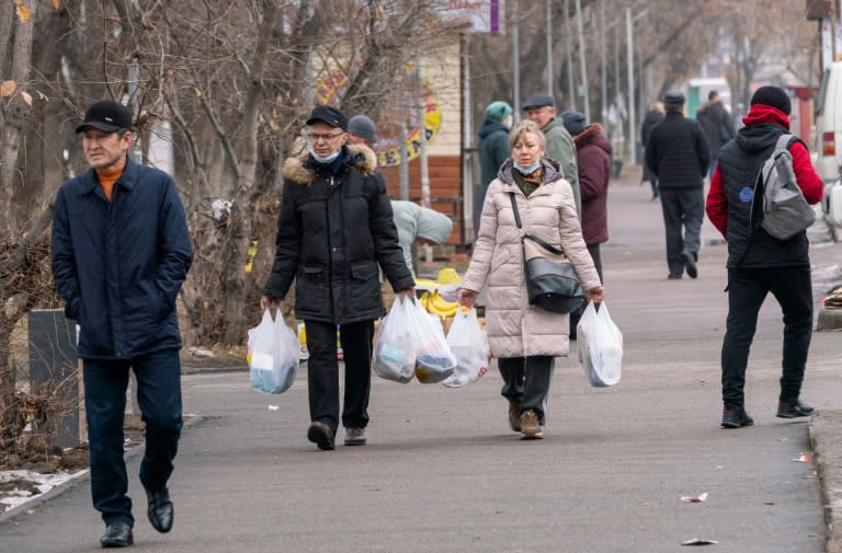 Habitantes de Almaty (Kazajistán) llevan bolsas de comida el 9 de enero de 2022 (AFP/Alexandr BOGDANOV)