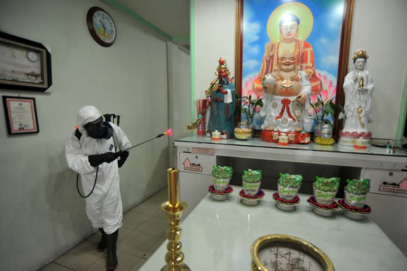 A police officer wearing a protective suit sprays disinfectant at a temple to prevent the spread of coronavirus disease (COVID-19) in Padang, West Sumatera Province, Indonesia