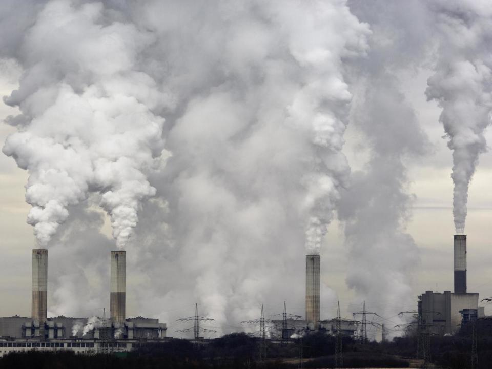 Smokestacks of a coal burning power plant with pollution on a cloudy day. (Getty)