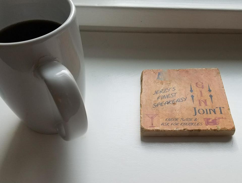 A mug next to two coasters with text; one says "Jerry's Finest Speakeasy" and the other mentions "Benjamin's Finest Speakeasy."