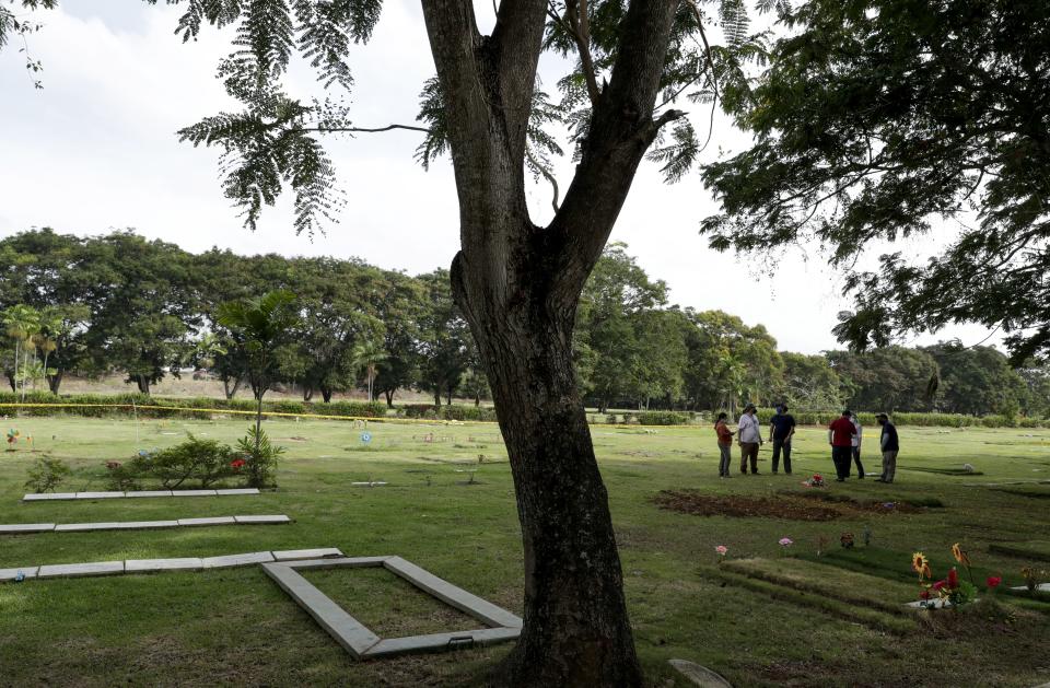 Forensic workers wait to begin an exhumation of what are believed to be the remains of Lt. Braulio Bethancourt, a victim of the 1989 U.S. invasion, at the Jardin de Paz cemetery in Panama City, Thursday, April 15, 2021. The prosecutor’s office has begun an exhumation of human remains at the Panamanian cemetery in a renewed attempt to confirm the identities of the victims of the U.S. invasion. (AP Photo/Arnulfo Franco)