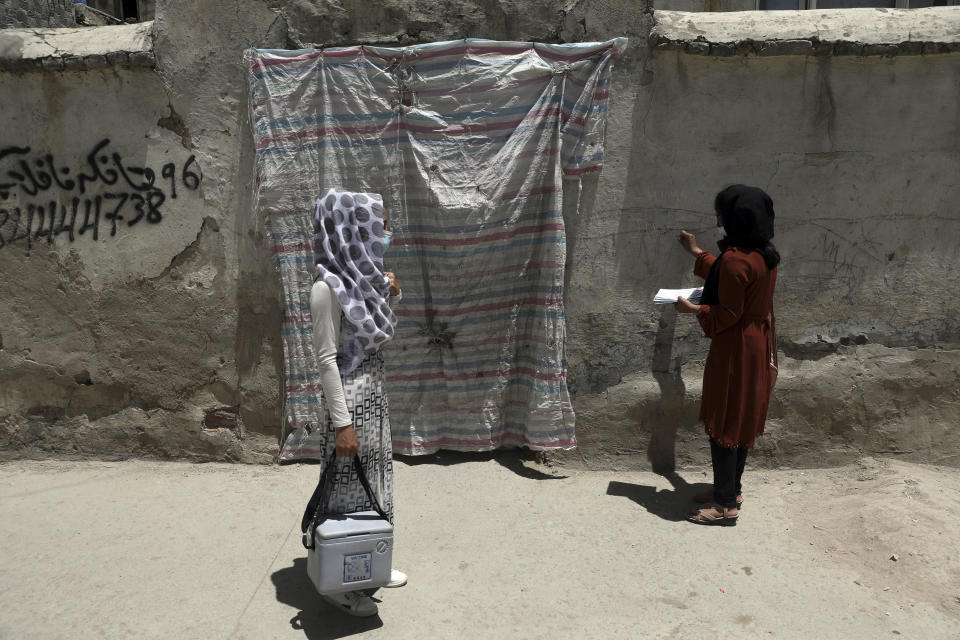 Health workers go door to door during a polio vaccination campaign in the old part of Kabul, Afghanistan, Tuesday, June 15, 2021. Gunmen on Tuesday targeted members of polio teams in eastern Afghanistan, killing a number of staffers, officials said. (AP Photo/Rahmat Gul)