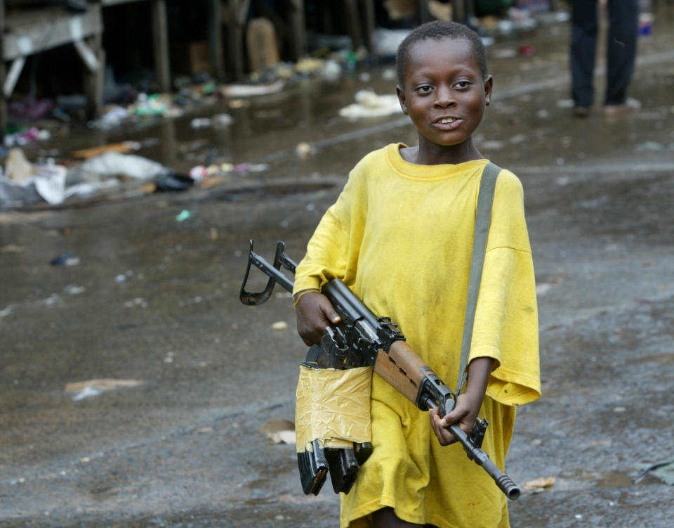 <p>A small boy brandishes an assault rifle near the front lines August 3, 2003 in Monrovia, Liberia. Very small children often hang around the fronts, learning to carry weapons in preparation as roles as fighters. Fighting has been dragging on for nearly two weeks now, leaving downtown’s social services nearly non-existent. (Photo by Chris Hondros/Getty Images) </p>