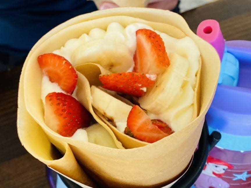 A crepe filled with cream, strawberry slices and banana slices.