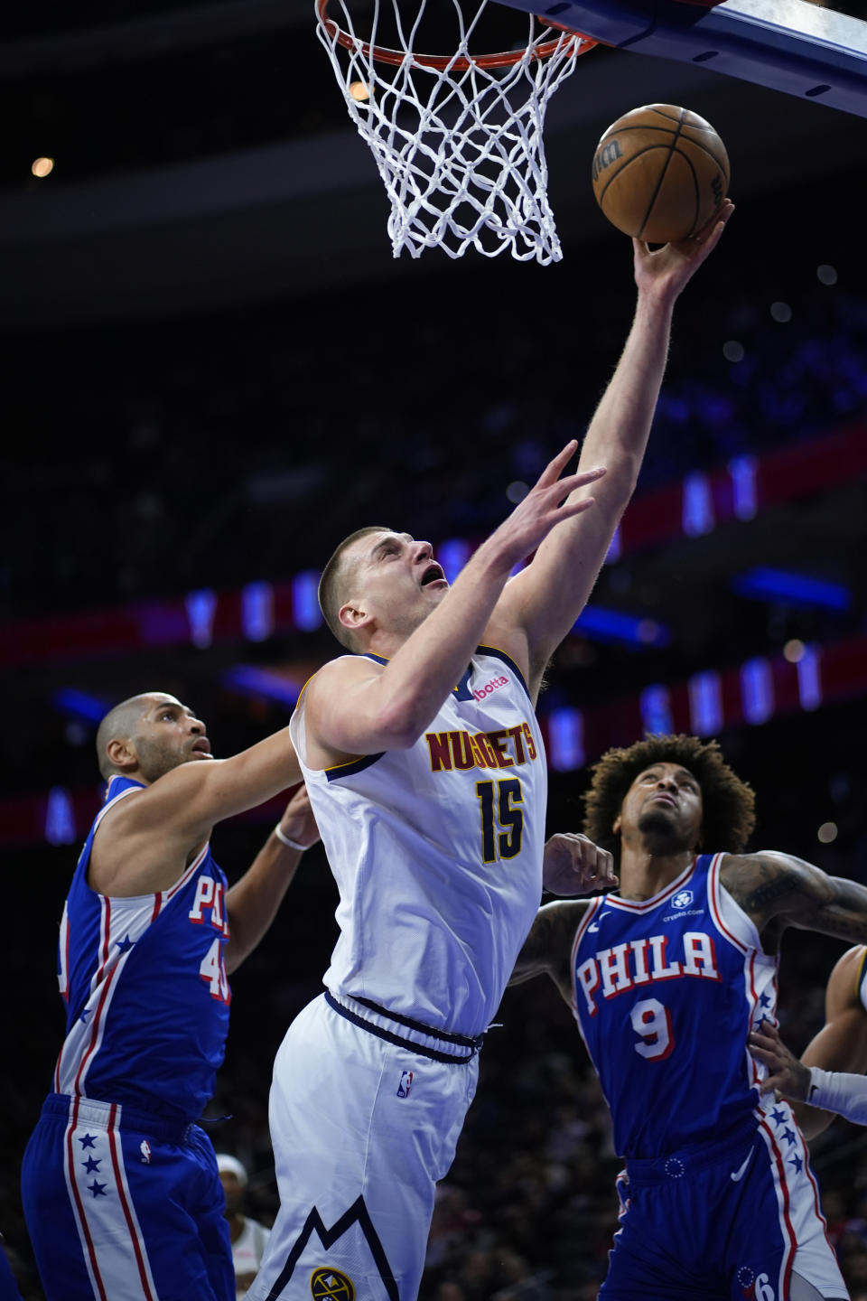 Denver Nuggets' Nikola Jokic, center, goes up for a shot against Philadelphia 76ers' Nicolas Batum, left, and Kelly Oubre Jr. during the first half of an NBA basketball game, Tuesday, Jan. 16, 2024, in Philadelphia. (AP Photo/Matt Slocum)