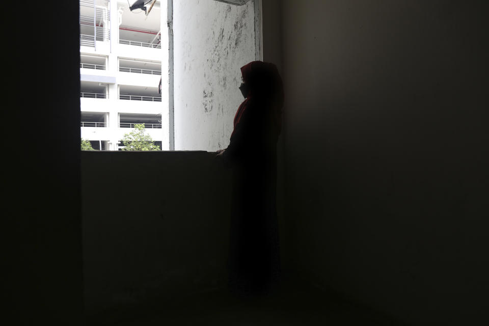 Rohingya child bride, R, age 14, stands next to a window in the hallway of an apartment complex in Kuala Lumpur, Malaysia, on Oct. 5, 2023. The complex houses several underage Rohingya girls who are married to older men. R left Myanmar for Malaysia in 2023 and is now married to an older man who verbally abuses her, she says. (AP Photo/Victoria Milko)