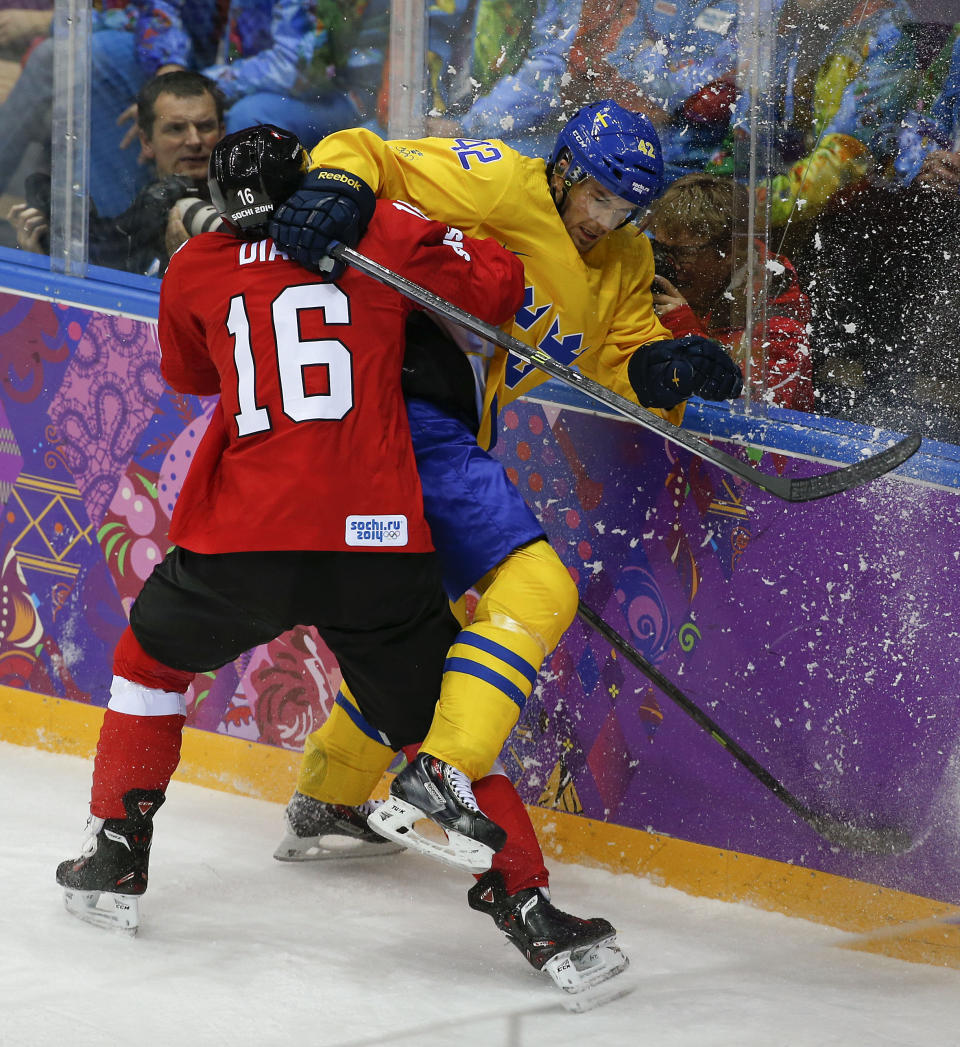 Switzerland defenseman Raphael Diaz checks Sweden forward Jimmie Ericsson in the first period of a men's ice hockey game at the 2014 Winter Olympics, Friday, Feb. 14, 2014, in Sochi, Russia. (AP Photo/Julio Cortez)