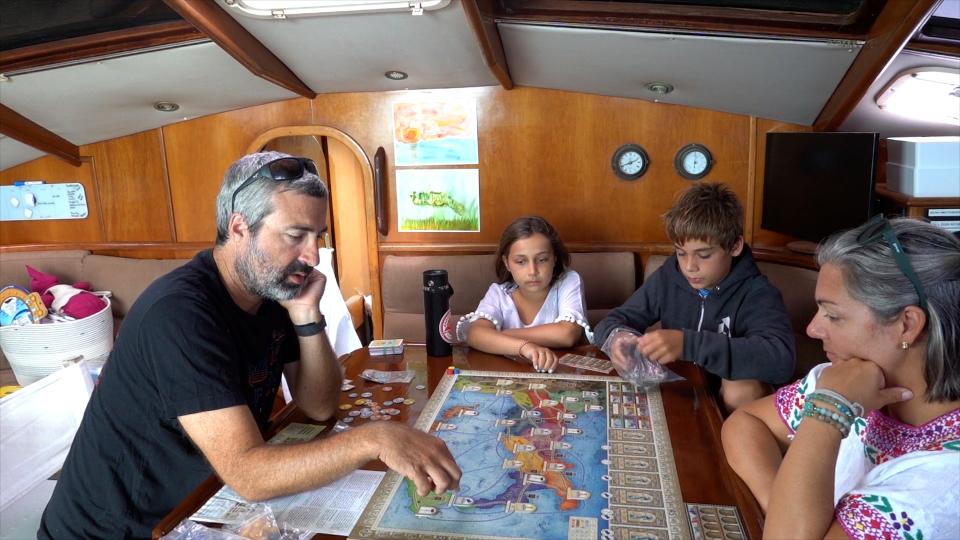 It's game time in the cabin below deck aboard "Scout": Nate, Eily, Kieran, and Megan consider the sailing days ahead.