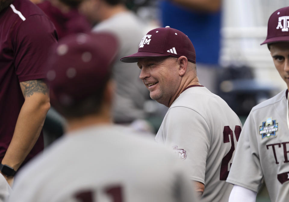 Texas A&M coach Jim Schlossnagle smiles in the dugout before his team plays against Tennessee in Game 1 of the NCAA College World Series baseball finals in Omaha, Neb., Saturday, June 22, 2024. (AP Photo/Rebecca S. Gratz)