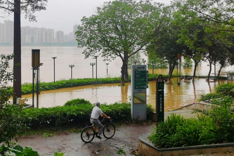 Una persona pasa en bicicleta por aguas crecidas de un río de Qingyuan, en el sur de China, el 21 de abril de 2024 (-)