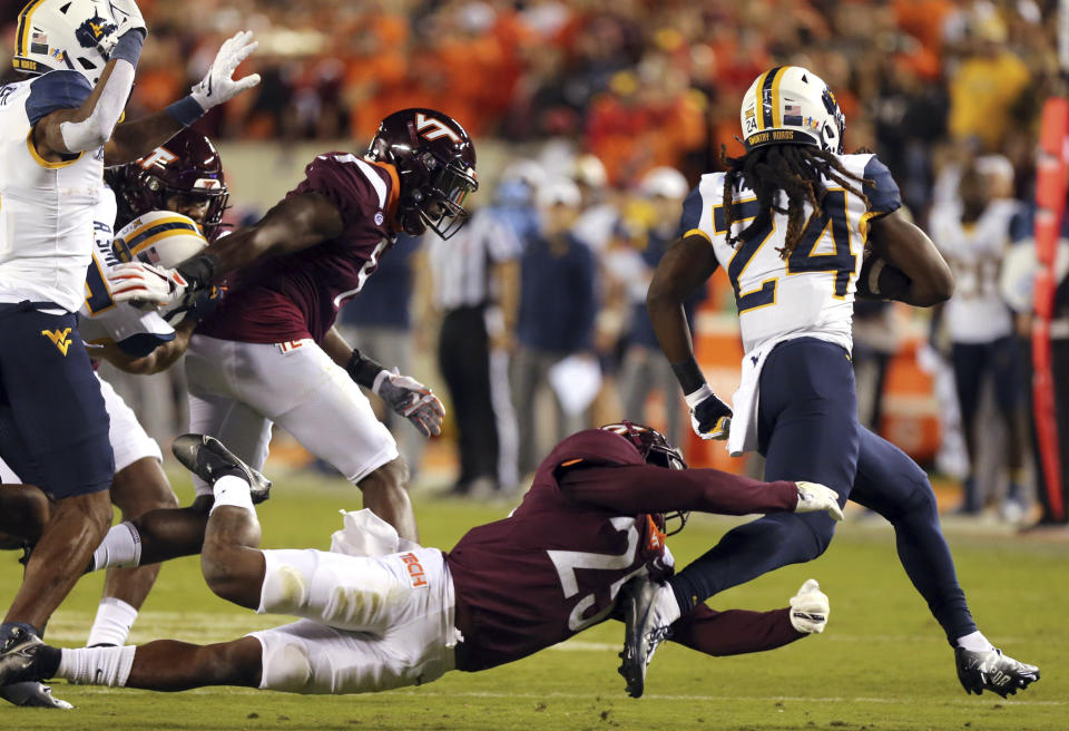 Virginia Tech's Chamarri Conner (25) dives for West Virginia running back Tony Mathis Jr. (24) during the first half of an NCAA college football game Thursday, Sept. 22, 2022, in Blacksburg, Va. (Matt Gentry/The Roanoke Times via AP)