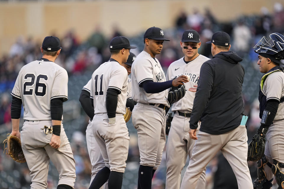 New York Yankees starting pitcher Jhony Brito, middle, hands the game ball to manager Aaron Boone during the third inning of a baseball game against the Minnesota Twins, Monday, April 24, 2023, in Minneapolis. (AP Photo/Abbie Parr)