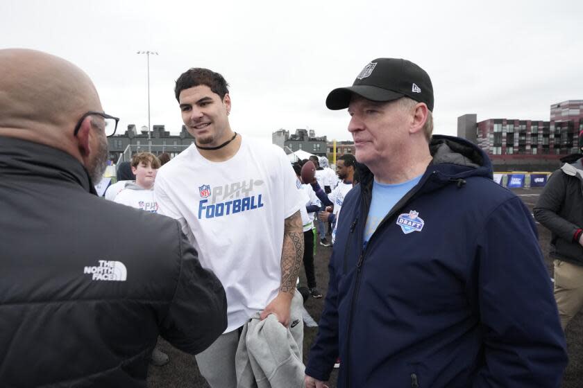 UCLA's Laiatu Latu, center, and NFL commissioner Roger Goodell walk off a field in Detroit.