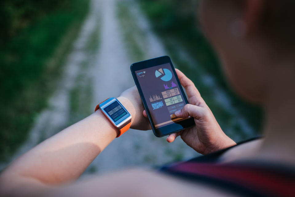 Woman synchronizing her smart watch and mobile device with the new data from workout.