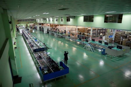 A worker cleans the floor near a TV assembly line, at a factory in Bangkok