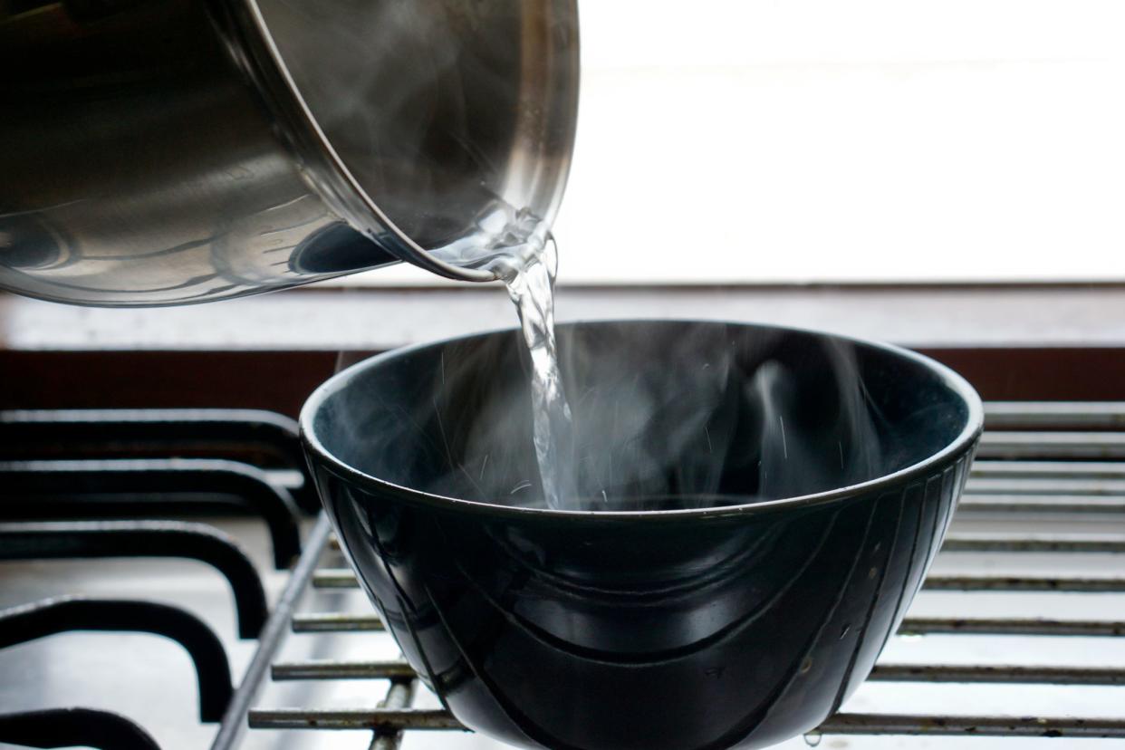 close up of pouring hot water to the bowl with vapor