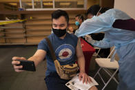 FILE - In this April 12, 2021, file photo, Freeson Wong, 31, takes a selfie as he receives a dose of the Moderna vaccine at a vaccination center in the Chinatown neighborhood of Los Angeles. The United States opened more distance between itself and much of the rest of the world on Thursday, April 15, nearing the 200 millionth vaccine administered in a months-long race to protect the population against COVID-19, even as other countries, rich and poor, struggle with stubbornly high infection rates and deaths. (AP Photo/Jae C. Hong, File)