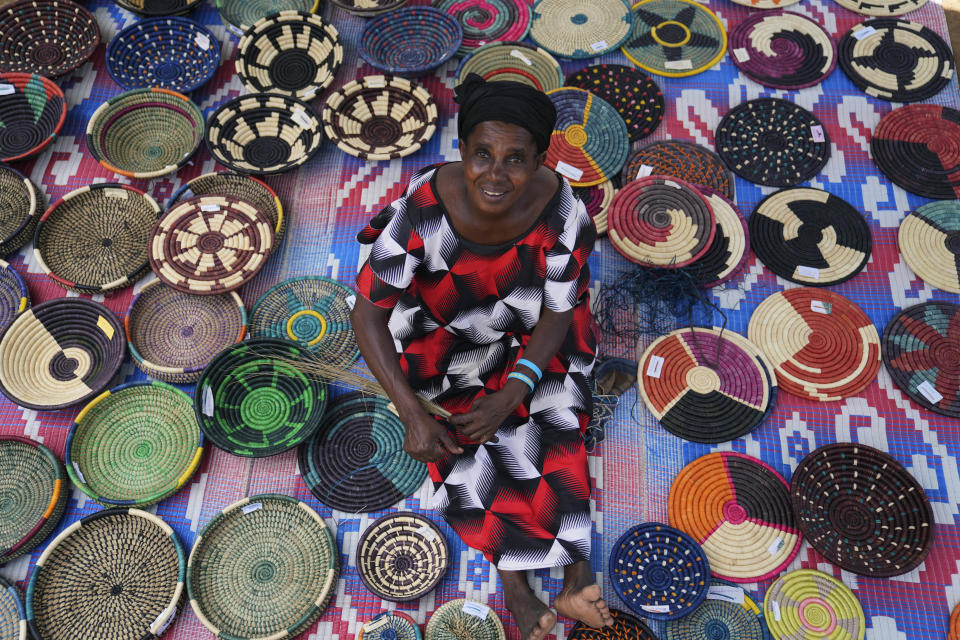 Anasitasia Nyirabashyitsi, 54, weaves a grass and thread bowl outside her home at Mybo reconciliation village in Nyamata, Rwanda, Friday, April 5, 2024. More than half the residents of this reconciliation village are women, and their projects — which include a basket-weaving cooperative as well as a money saving program — have united so many of them that it can seem offensive to inquire into who is Hutu and who is Tutsi. (AP Photo/Brian Inganga)