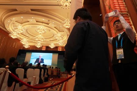 A worker takes a photo with his phone as Angel Gurria, Secretary-General of OECD speaks on stage at the High-level Tax Symposium held in Chengdu in Southwestern China's Sichuan province, Saturday, July 23, 2016. REUTERS/Ng Han Guan/Pool