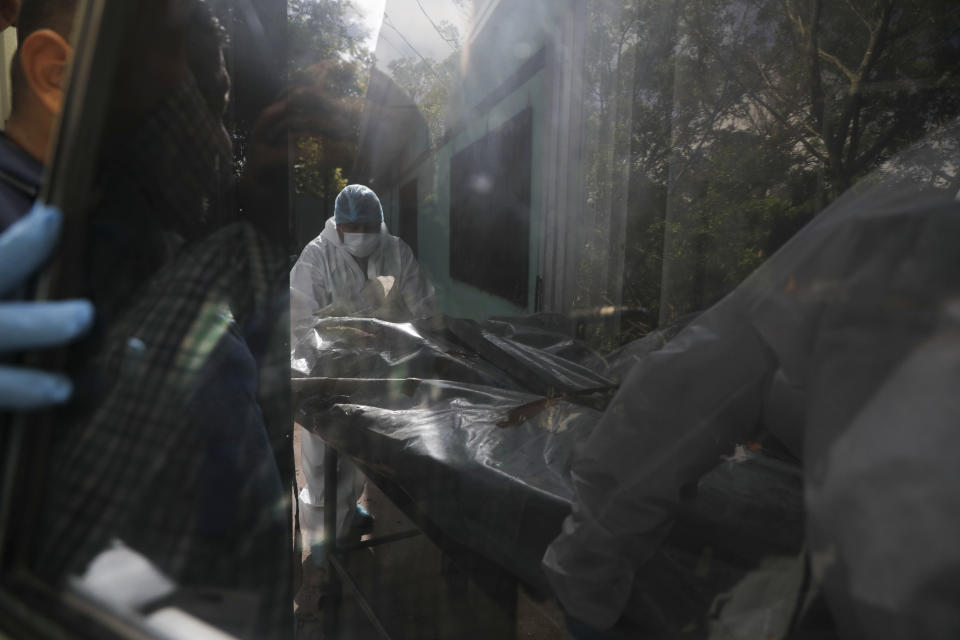 Expertos forenses descargan un cuerpo extraído de una prisión de mujeres en la morgue médica en Tegucigalpa, Honduras, el miércoles 21 de junio de 2023. (AP Foto/Elmer Martínez)