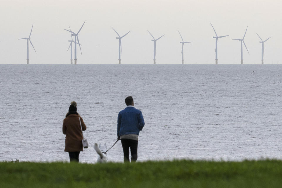 Some lenders are starting to offer green mortgages with incentives such as lower interest rates for less wasteful buildings. Above, a couple look out at wind turbines off the coast of Essex in Frinton-on-Sea, England. Photo: Dan Kitwood/Getty Images