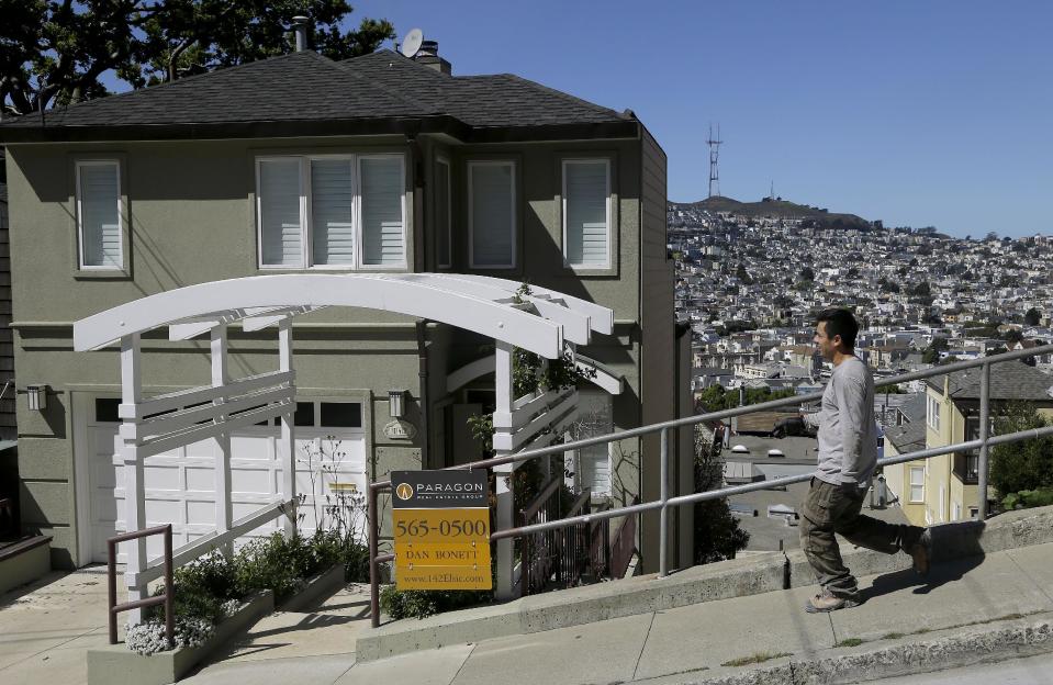 A man walks past a home for sale in San Francisco, Monday, March 17, 2014. San Francisco will now lend as much as $200,000 to some homebuyers toward a down payment on their first house or condominium. Mayor Ed Lee's decision to double the previous limit of $100,000 was intended to help middle-class residents who have been hit hard by the housing crunch. (AP Photo/Jeff Chiu)