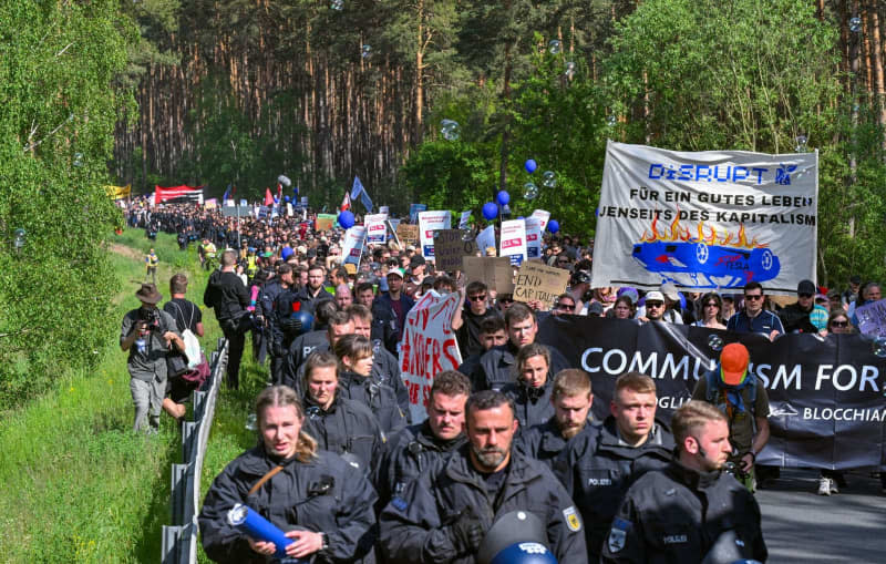 Environmental activists walk to the Tesla plant during a protest against Tesla. After sometimes violent clashes on May 10, 2024 at the Tesla factory site in Gruenheide near Berlin, new protests are currently underway against the US company. Patrick Pleul/dpa