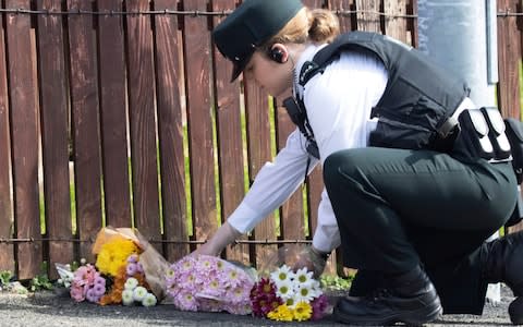 A police officer lays down flowers at the site of Lyra McKee's murder - Credit: JOE BOLAND/NORTH WEST NEWSPIX/EPA-EFE/REX 