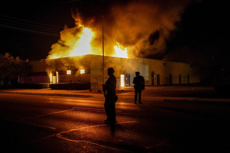 Police stand near a department of corrections building that was on fire during protests, Monday, Aug. 24, 2020, in Kenosha, Wis., sparked by the shooting of Jacob Blake by a Kenosha Police officer a day earlier. (AP Photo/Morry Gash)