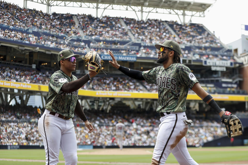 San Diego Padres left fielder Juan Soto and right fielder Fernando Tatis Jr. high-five at the end of the third inning during a baseball game against the Boston Red Sox, Sunday, May 21, 2023, in San Diego. (AP Photo/Brandon Sloter)