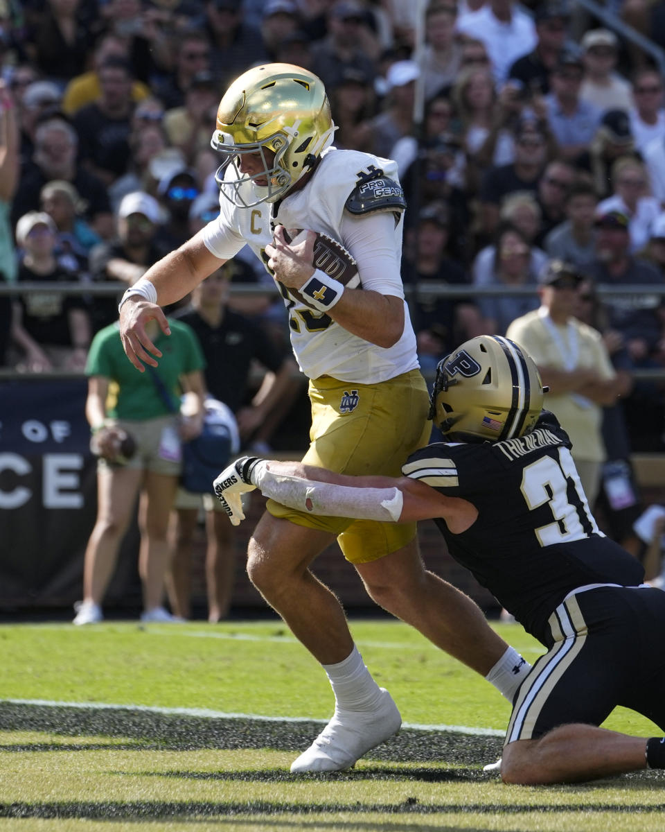 Notre Dame quarterback Riley Leonard (13) is hit by Purdue defensive back Dillon Thieneman (31) as he runs in for a touchdown during the first half of an NCAA college football game in West Lafayette, Ind., Saturday, Sept. 14, 2024. (AP Photo/Michael Conroy)