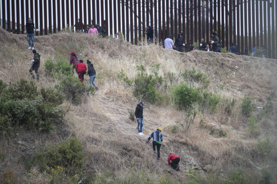 SAN DIEGO, CALIFORNIA, UNITED STATES - 2023/05/12: Asylum seekers are seen scaling a hill between the US-Mexico border to reach the Mexican military who was providing aid alongside the US volunteers / Credit: Jon Putman/SOPA Images/LightRocket via Getty Images