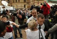 Olympic and Paralympic track star Oscar Pistorius (R) is hugged by a supporter as he arrives ahead of his trial for the murder of his girlfriend Reeva Steenkamp at the North Gauteng High Court in Pretoria, April 14, 2014. Pistorius is on trial for murdering Steenkamp at his suburban Pretoria home on Valentine's Day last year. He says he mistook her for an intruder. REUTERS/Siphiwe Sibeko (SOUTH AFRICA - Tags: SPORT ATHLETICS CRIME LAW)