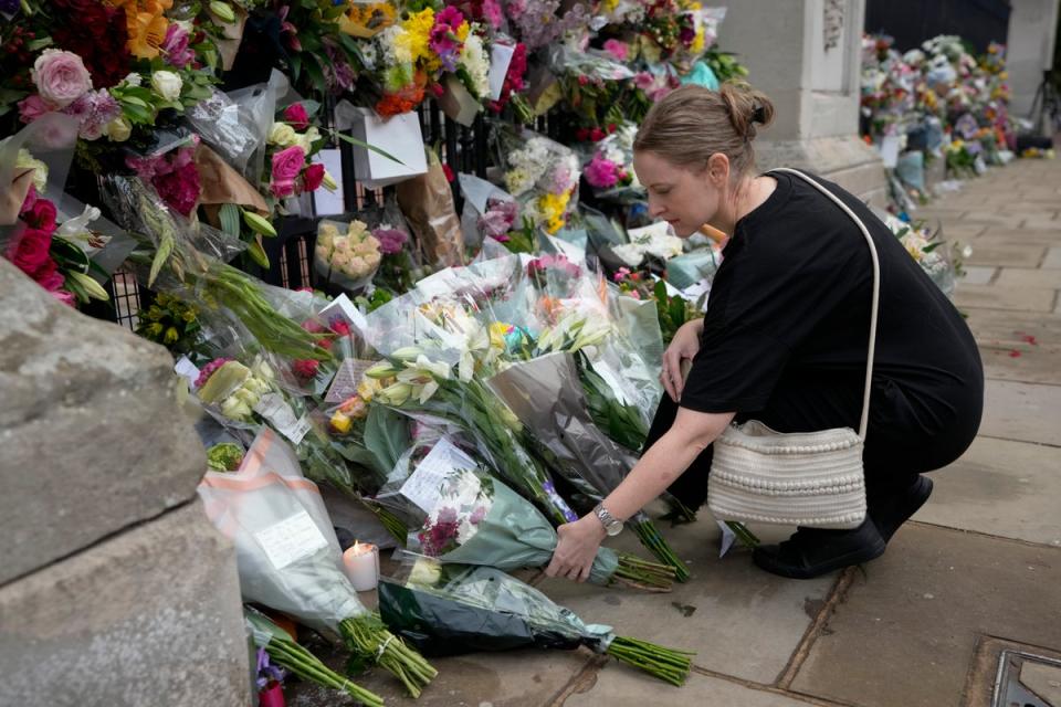 A mourner lays flowers outside Buckingham Palace in London (AP)