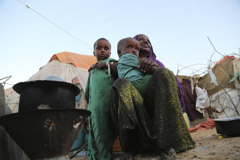 Una mujer desplazada con sus hijos cocina cerca de su carpa improvisada en el campamento Daynile en Mogadiscio, Somalia, el jueves 17 de diciembre de 2020. (AP Foto/Farah Abdi Warsameh)