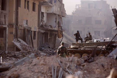 Syrian army soldiers sit on a military vehicle at a damaged site in al-Hajar al-Aswad, Syria May 21, 2018. REUTERS/Omar Sanadiki