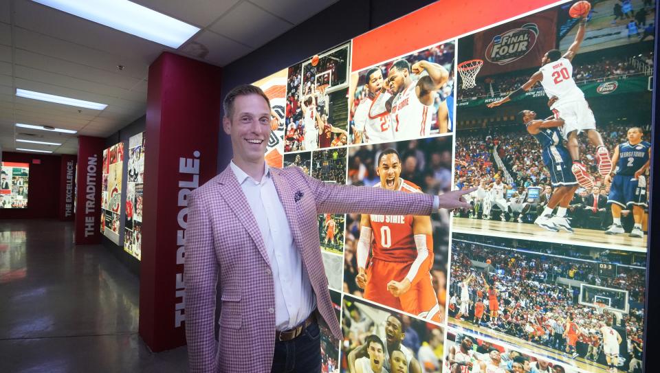 Jul 24, 2023; Columbus, Ohio. In a basement hallway inside the Schottenstein Center,  Former Ohio State men's basketball player Matt Terwilliger laughs as he points to a picture of him sitting on the bench watching Greg Oden dunk a basketball during a Final Four game. Terwilliger is watching the dunk with his mouth wide open. Since leaving basketball, Terwilliger is running his own wealth advisory company. 