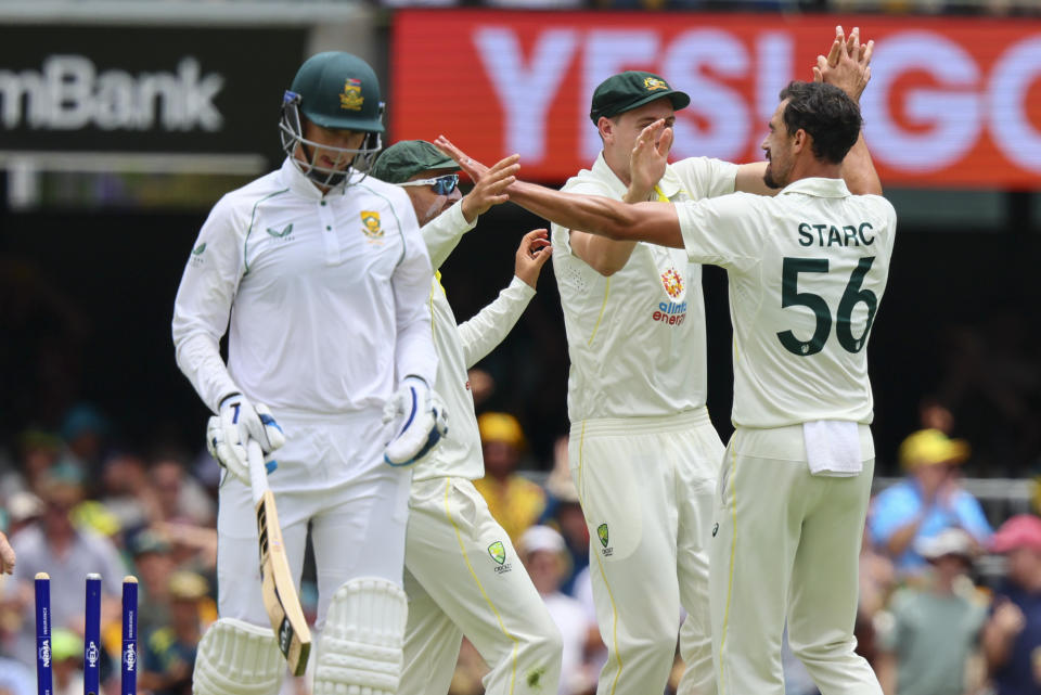Australia's Mitchell Starc, right, is congratulated by teammates after dismissing South Africa's Rassie van der Dussen, left, during day two of the first cricket test between South Africa and Australia at the Gabba in Brisbane, Australia, Sunday, Dec.18, 2022. (AP Photo/Tertius Pickard)