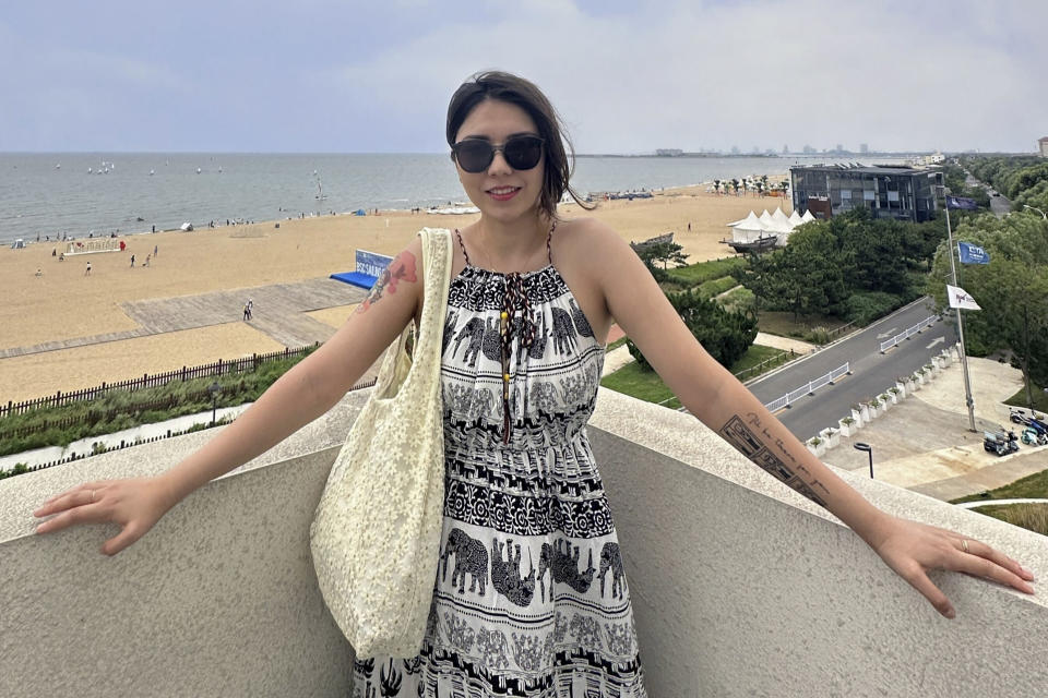In this photo released by Nilufar Arkin, Nilufar Arkin poses for a photo in Qinhuangdao in northern China's Hebei province, on Aug. 24, 2023. Nilufar Arkin, who lives in Tianjin, says she and her boyfriend have been described by their friends as the real-life Monica and Chandler. The couple even got matching tattoos two years ago with the lyrics from the theme song "I'll Be There For You," performed by The Rembrandts. The artwork on their arms also depict the classic Thanksgiving scene where Monica dances in front of Chandler wearing a turkey on her head. It was the first time Chandler told Monica that he loved her. (Nilufar Arkin via AP)