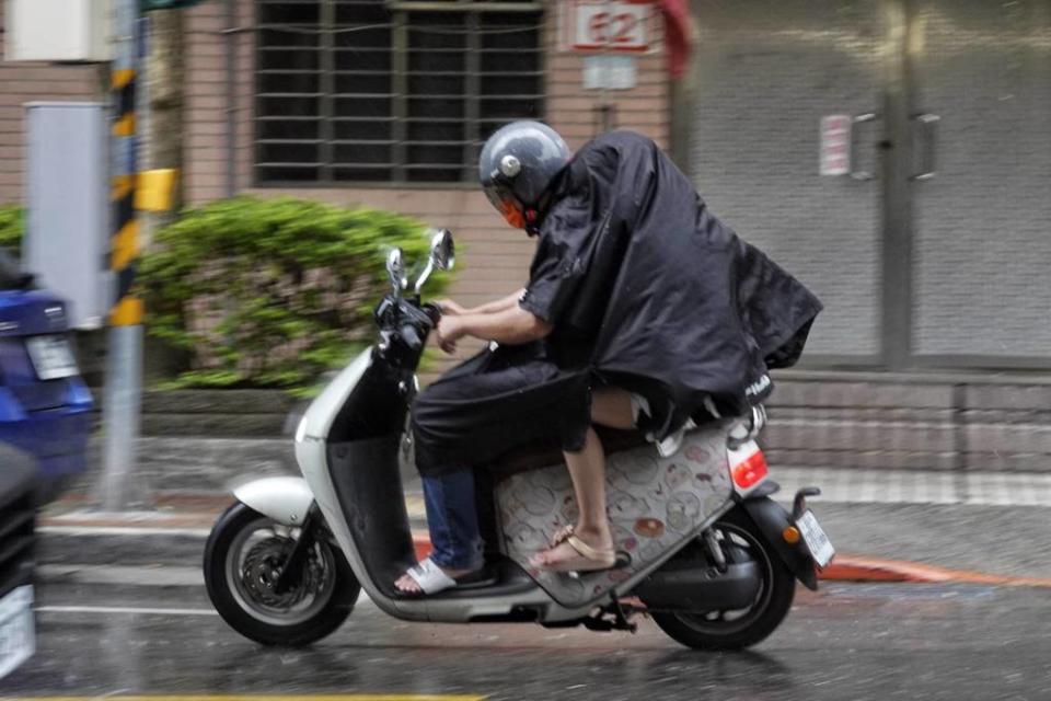 台北市25日下午突然降下大雨，圖為措手不及的機車族兩人共用一件雨衣。（黃子明攝）