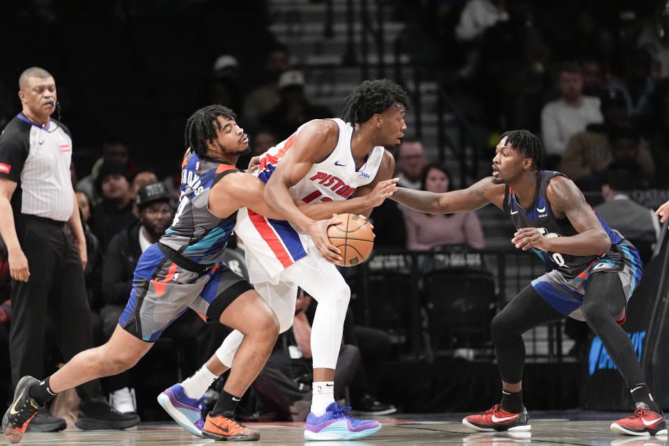 Brooklyn Nets guard Cam Thomas, front left, and forward Dorian Finney-Smith, right, guard against Detroit Pistons center James Wiseman, center, during the first half of an NBA basketball game, Saturday, April 6, 2024, in New York. (AP Photo/Mary Altaffer)