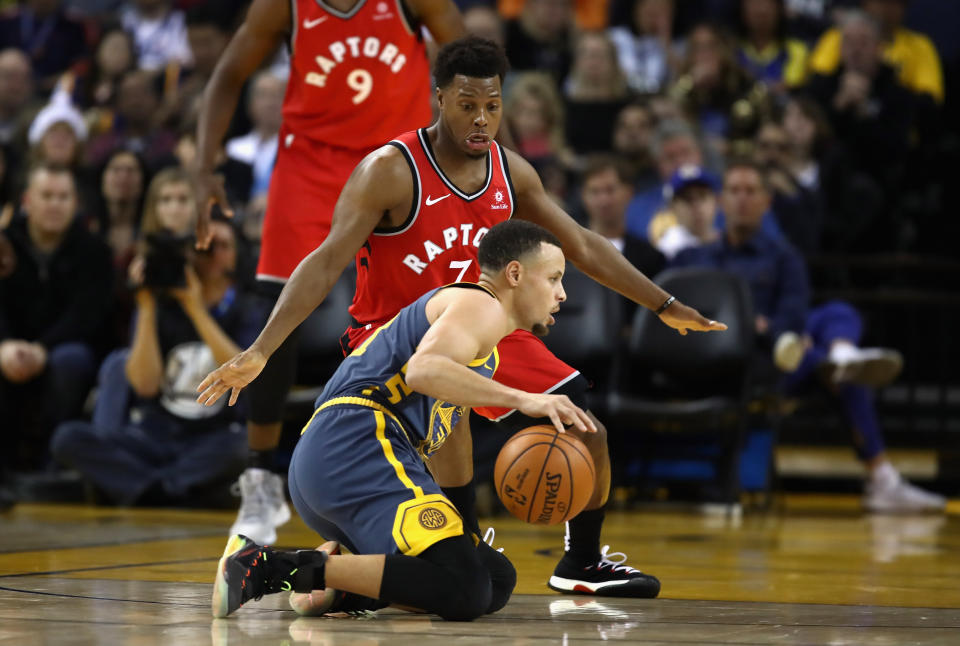 OAKLAND, CA - DECEMBER 12:  Stephen Curry #30 of the Golden State Warriors dribbles on his knees while being guarded by Kyle Lowry #7 of the Toronto Raptors at ORACLE Arena on December 12, 2018 in Oakland, California.  NOTE TO USER: User expressly acknowledges and agrees that, by downloading and or using this photograph, User is consenting to the terms and conditions of the Getty Images License Agreement.  (Photo by Ezra Shaw/Getty Images)