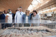 In this handout photo provided by the Prime Minister's Office , Greek Prime Minister Kyriakos Mitsotakis, second left, his wife Mareva Grabowski-Mitsotakis, second right, and Greek Culture Minister Lina Mendoni, right, looking at a scale model of the site during their visit in the archaeological site of Akrotiri at the Greek island of Santorini. Mitsotakis visited Santorini Saturday to announce the opening of the tourist season.(Dimitris Papamitsos/ Greek Prime Minister's Office via AP)