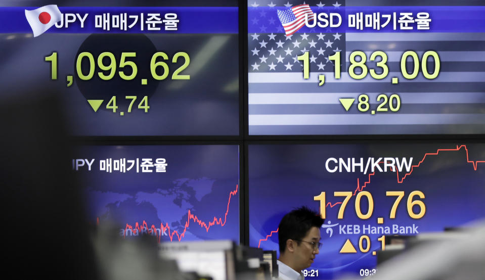 A currency trader walks by the screens showing the foreign exchange rates at the foreign exchange dealing room in Seoul, South Korea, Tuesday, June 4, 2019. Shares are mixed in Asia after a tumultuous session for tech shares on Wall Street. (AP Photo/Lee Jin-man)